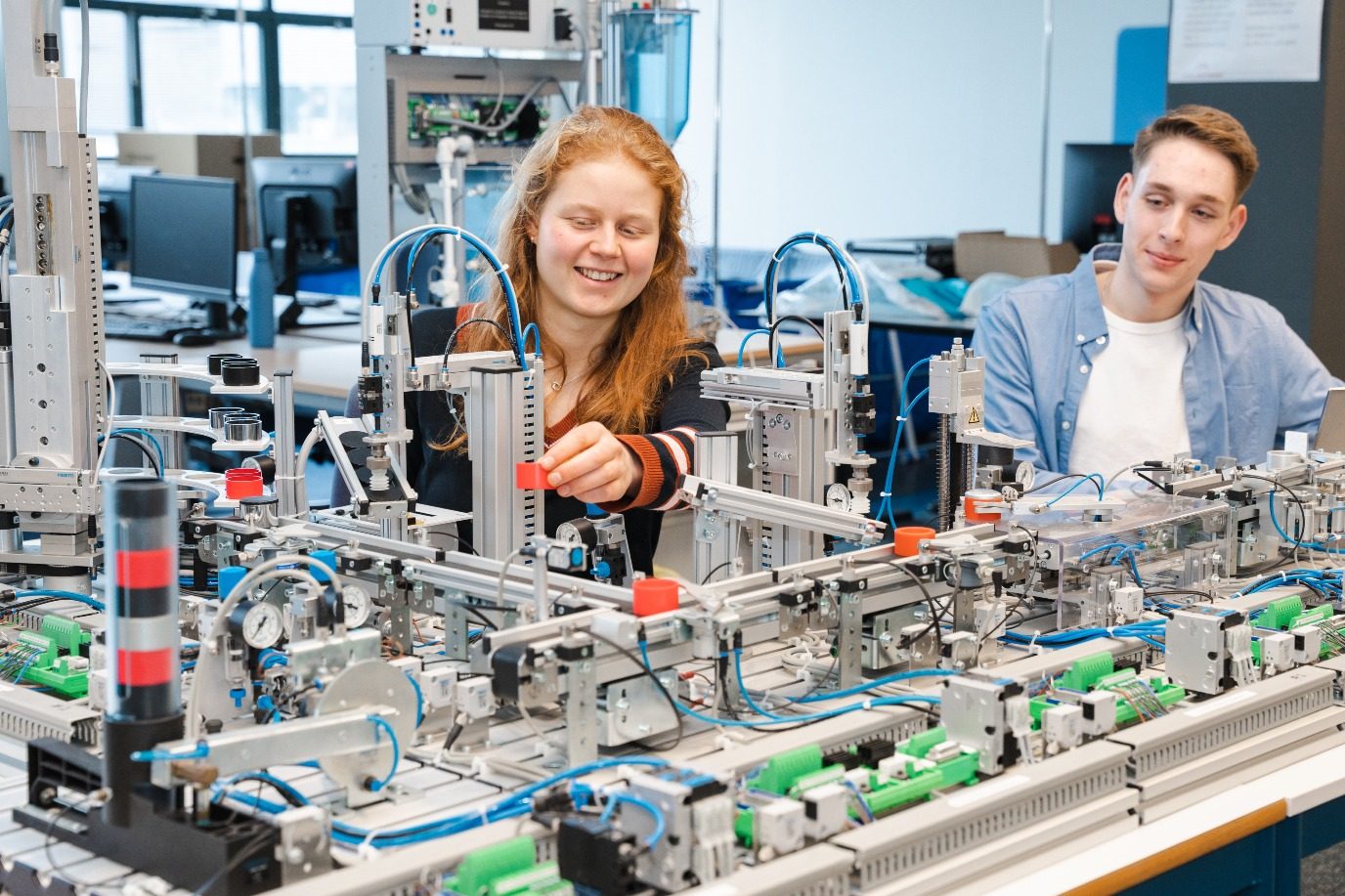 Two students working at a production automation training line
