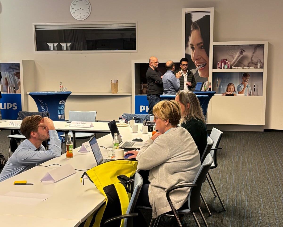 Participants at tables in a Philips meeting room in Drachten, with product displays on the wall