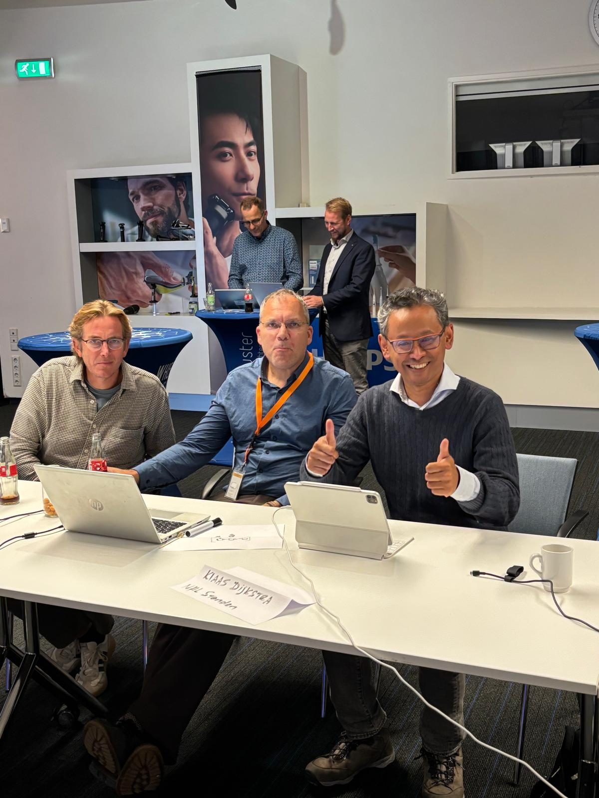 Three participants at a table during the roadmap session, one giving two thumbs up