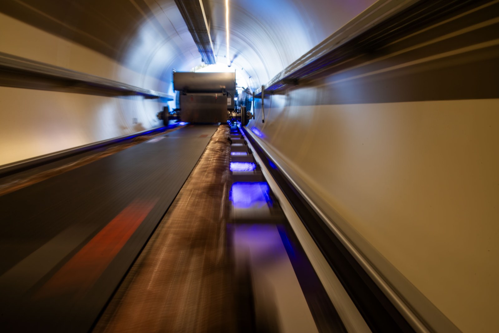 Long view along the inside of the goTube, with rails and blue lights running towards a vehicle in the distance