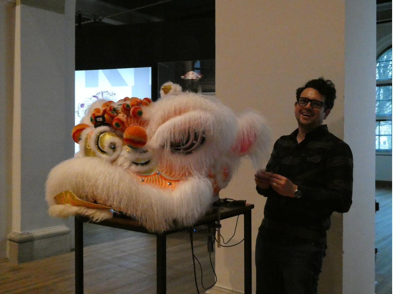 Mauricio laughing beside the robotic lion head at the Wereldmuseum