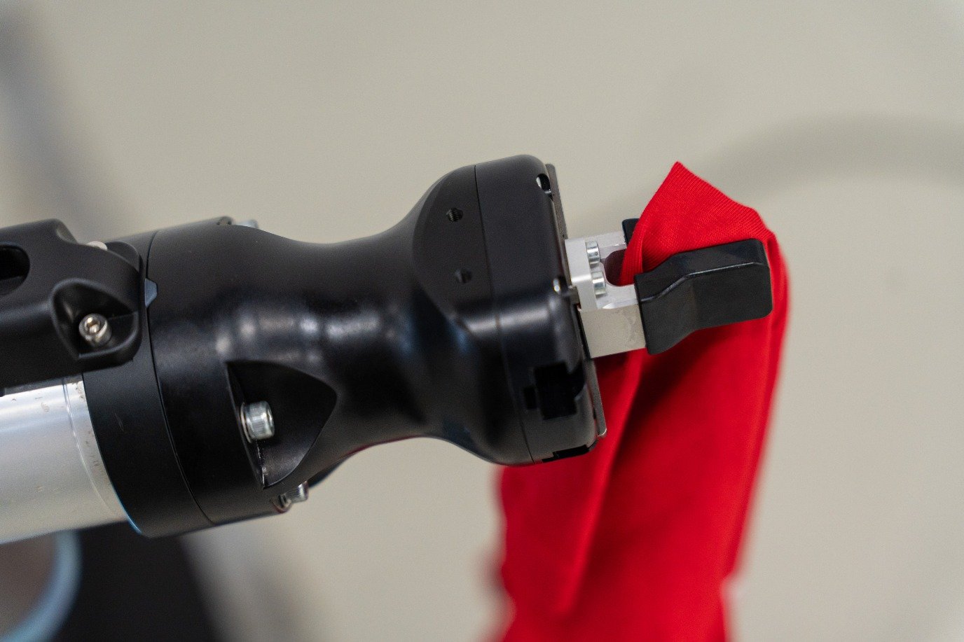 Close-up of a two-finger gripper pinching red fabric